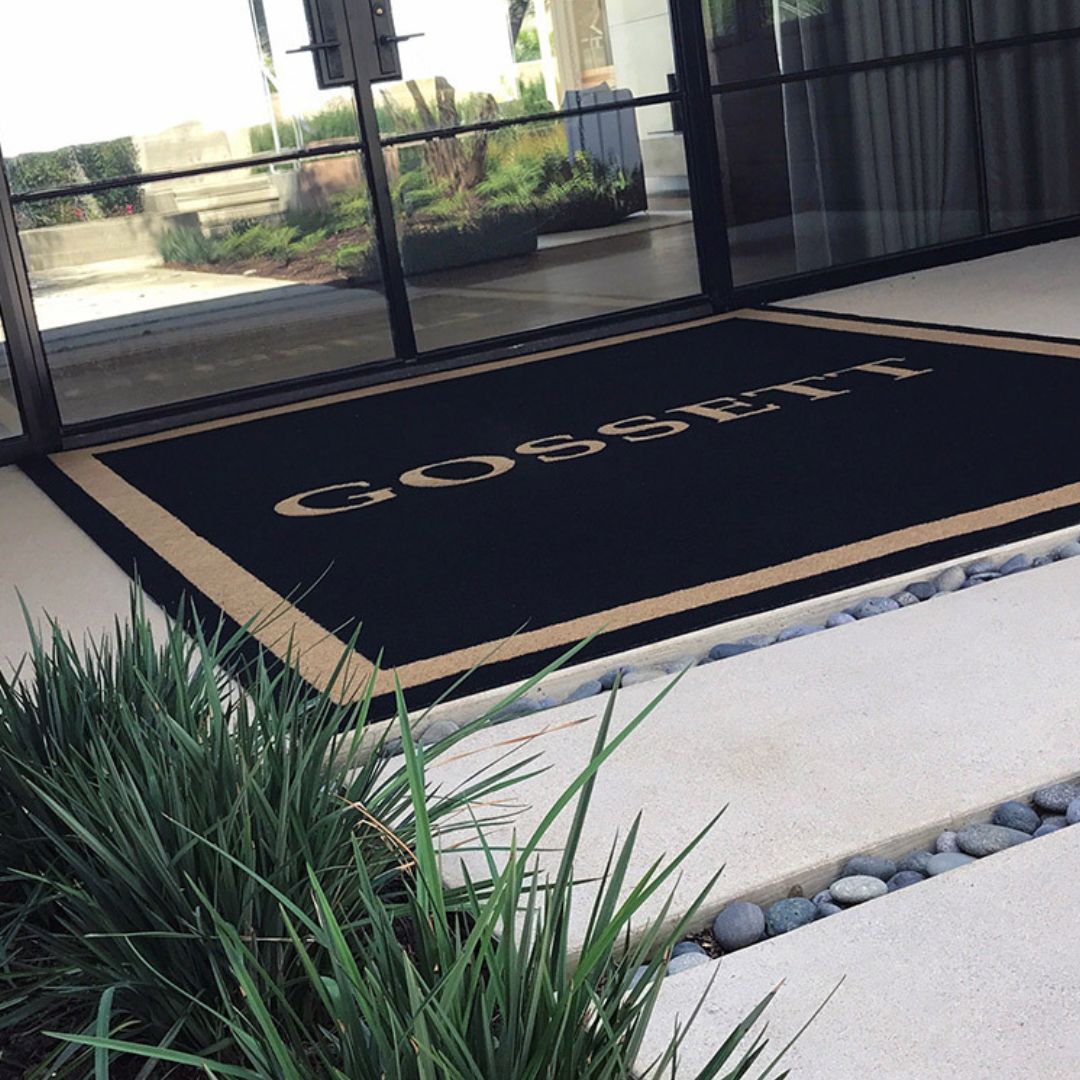 Custom doormat with large monogram design reading in front of door.