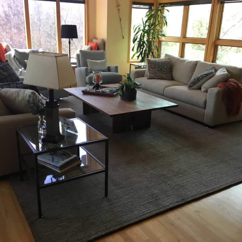 Dark grey area rug with dark greay couches.