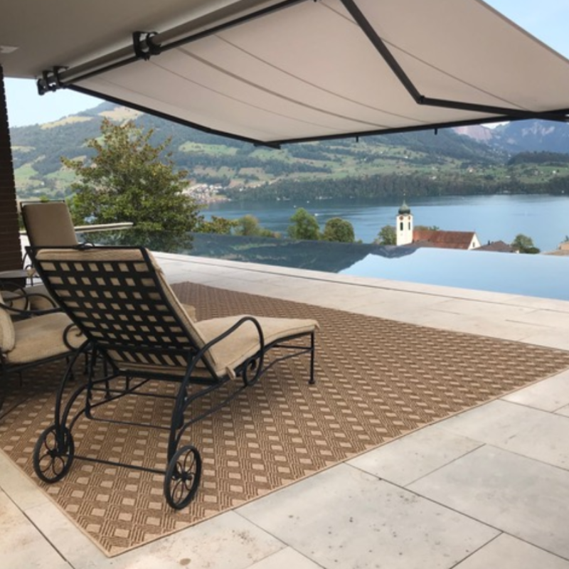 Beige outdoor area rug with patio furniture.