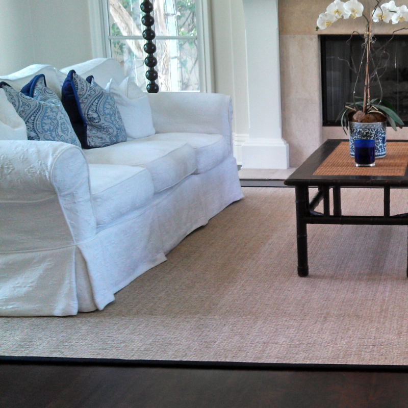 natural grass area rug with black border and white couch.