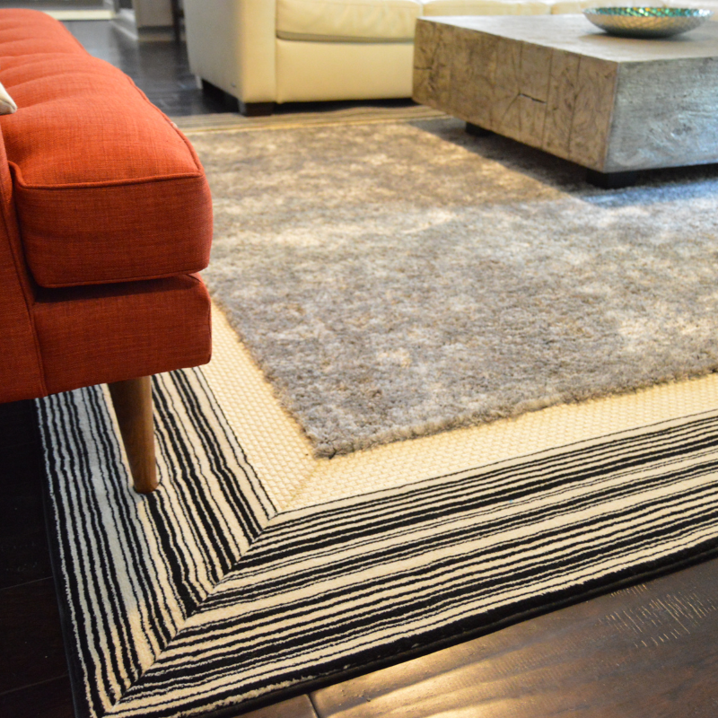 Gray and black area rug with orange chair.