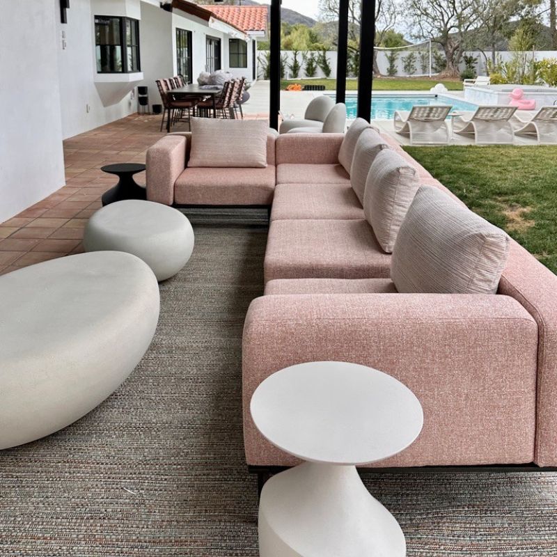 gray all weather outdoor rug with pink counch and white tables.