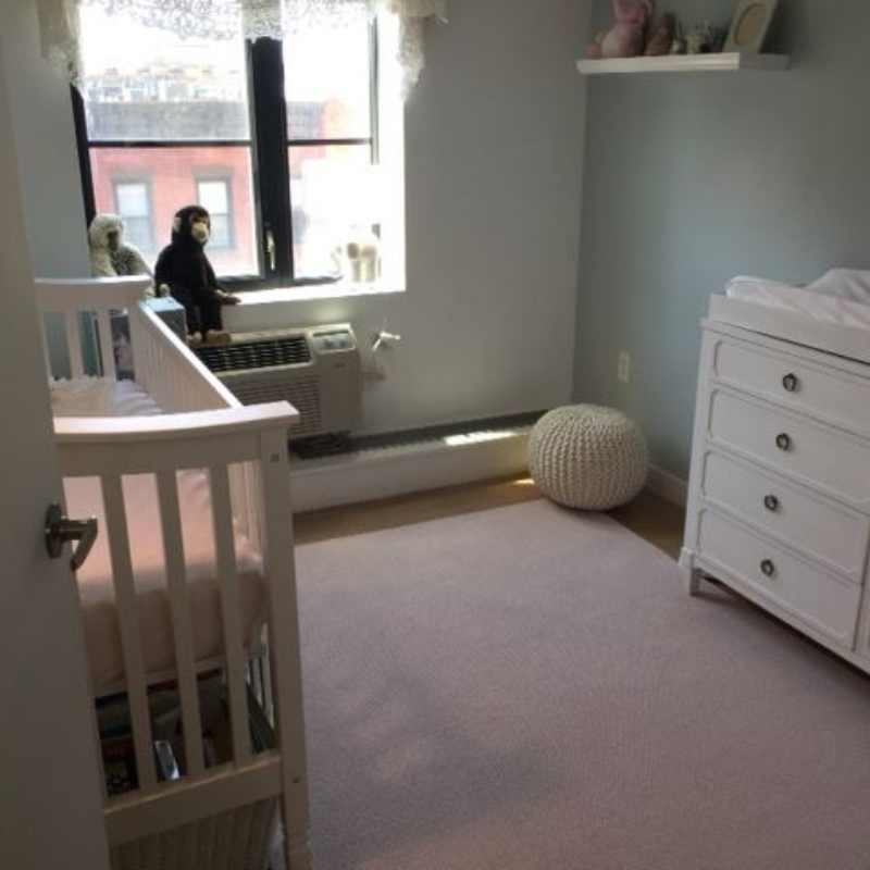Pink wool area rug with baby crib and changing table.